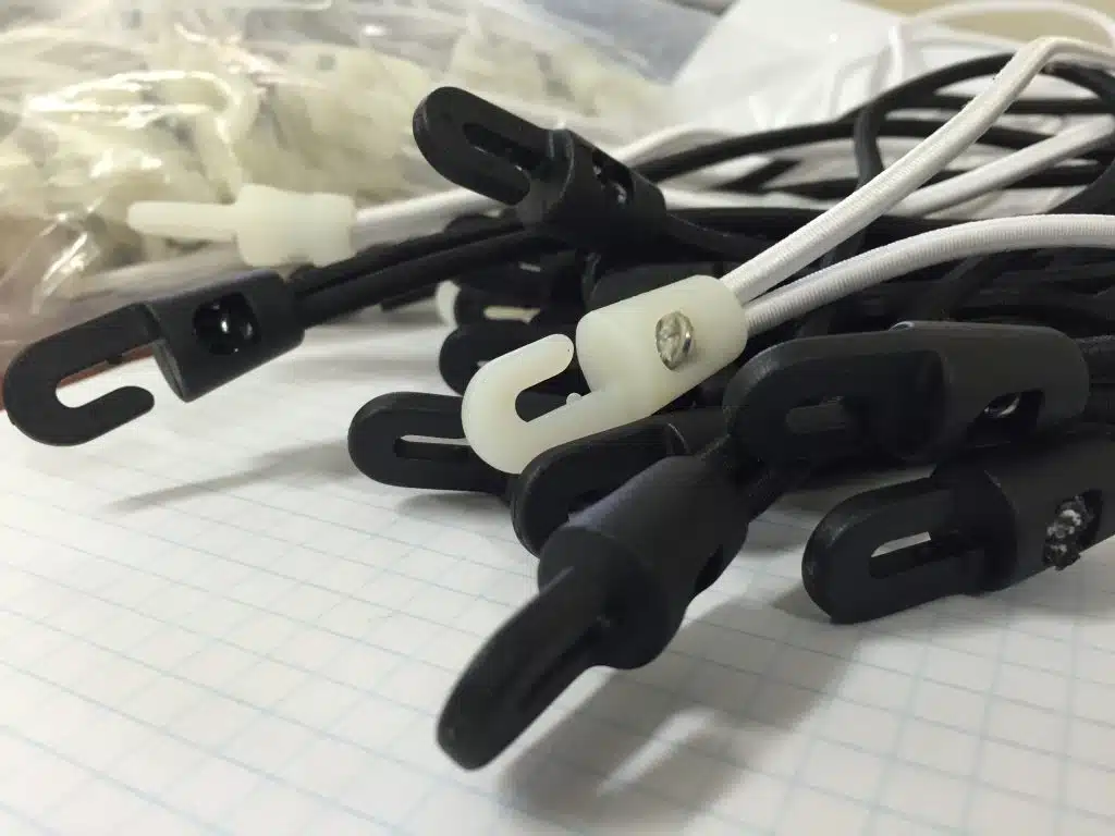 A close up of a handful of black and white bungies on a white surface.