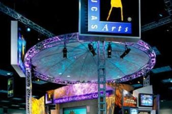 Multiple level structure inside a dark venue made of truss. Rectangular and circular softgoods are lite-up in varound soft shades of teal, pink, blue, and yellow.